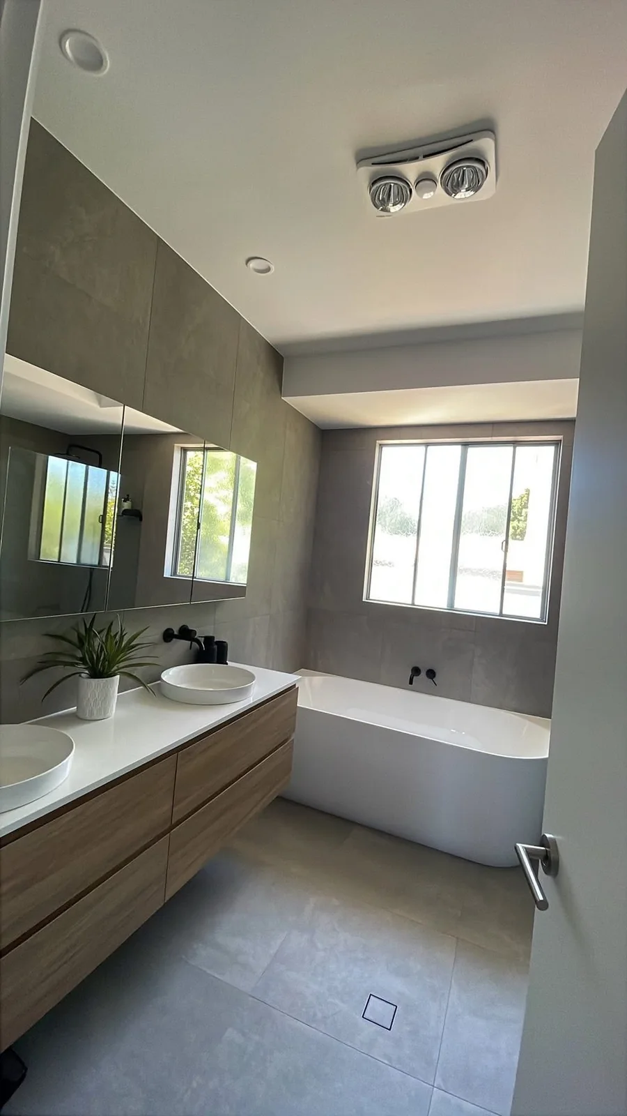 Grey tiled bathroom with double vanity and freestanding bath