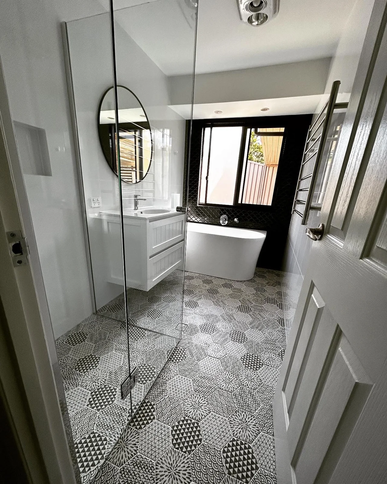 Bathroom with patterned hexagon floor tiles and freestanding bath